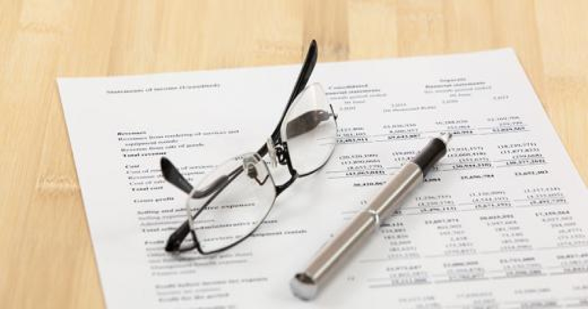 A fact sheet in a table with eyeglasses and a pen on top.