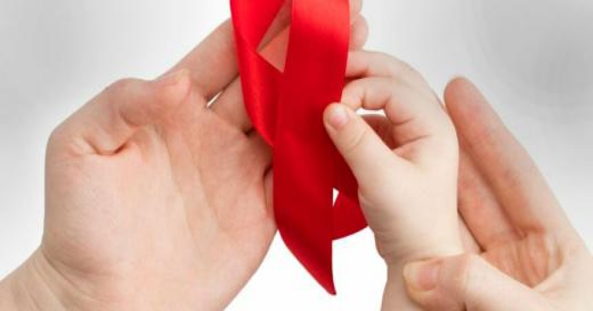 The infant's and adult's hands holding a red ribbon.