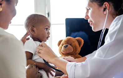 Doctor verificando a bebé con un peluche cerca.