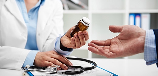 A physician handing a bottle to the patient. 